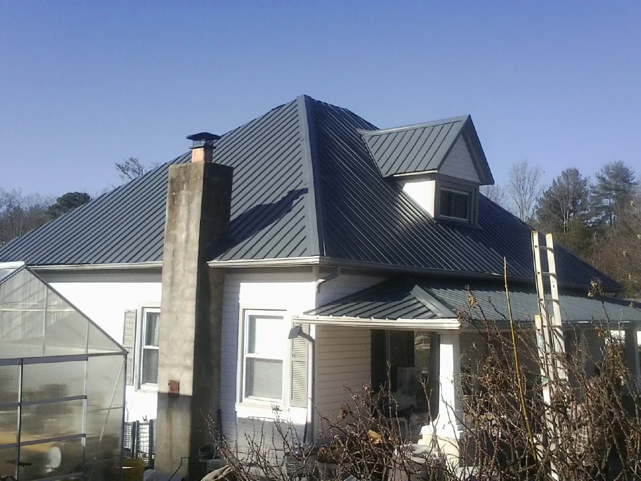 Dark blue standing seam metal roof on a white farmhouse with dormer — Slate & Tile Roof Repair by Roofing Brothers in Riverdale